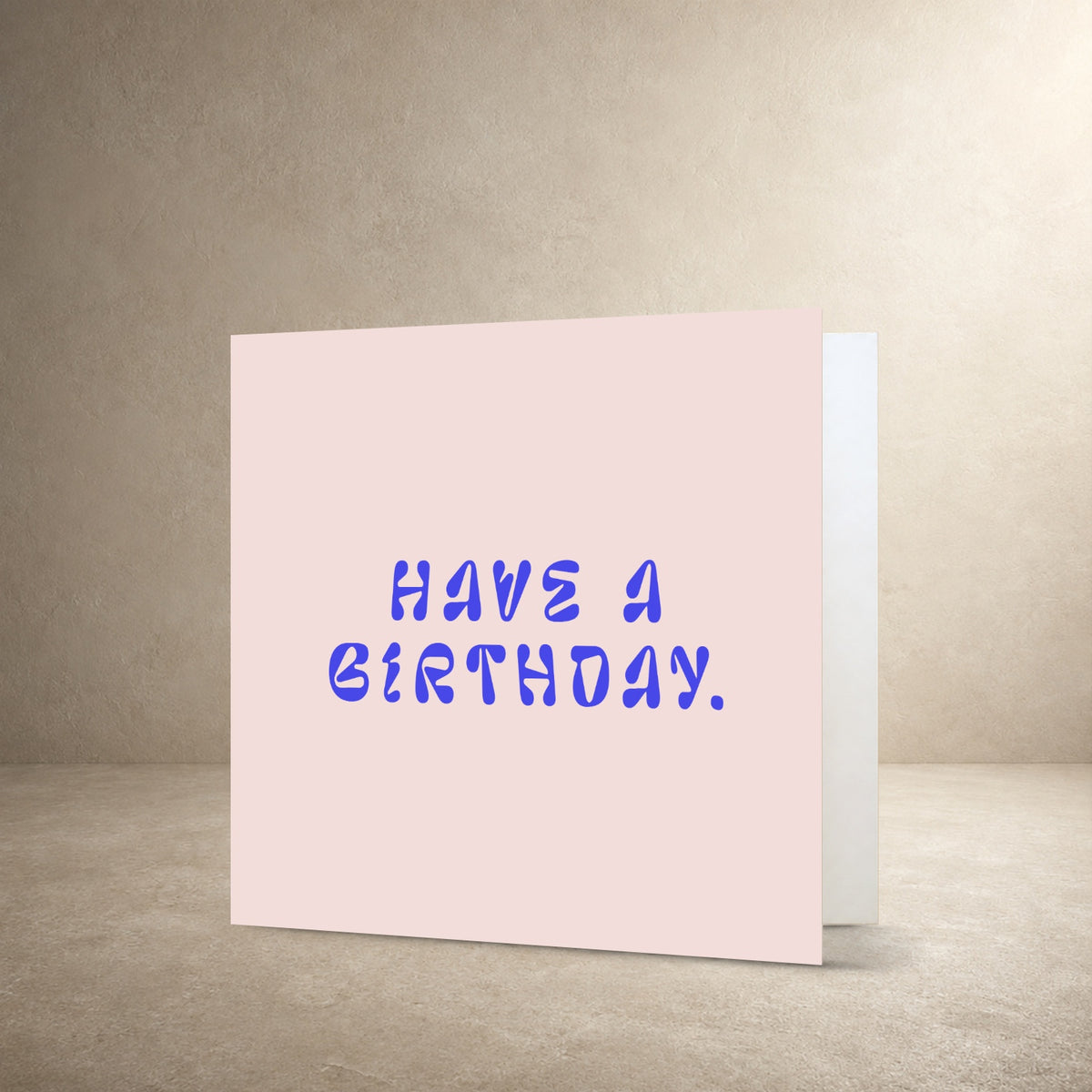 Pale pink card front with bold irregular blue typography, with the message: “Have a birthday.”.