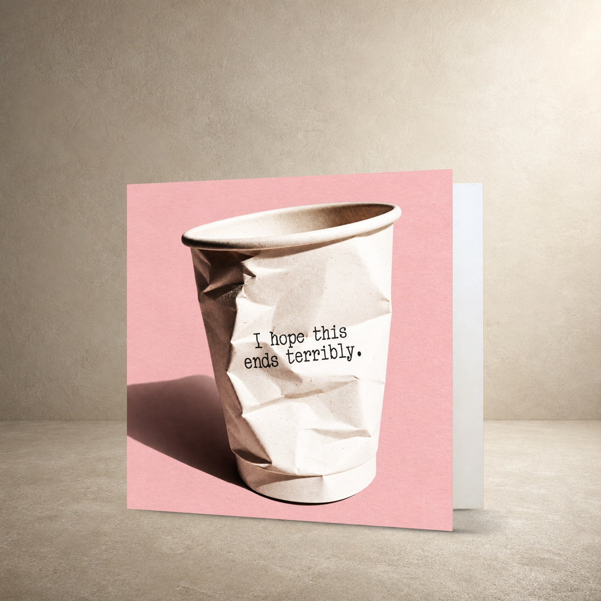 Crumpled white paper cup on a textured pink background, with the message: “I hope this ends terribly.”.