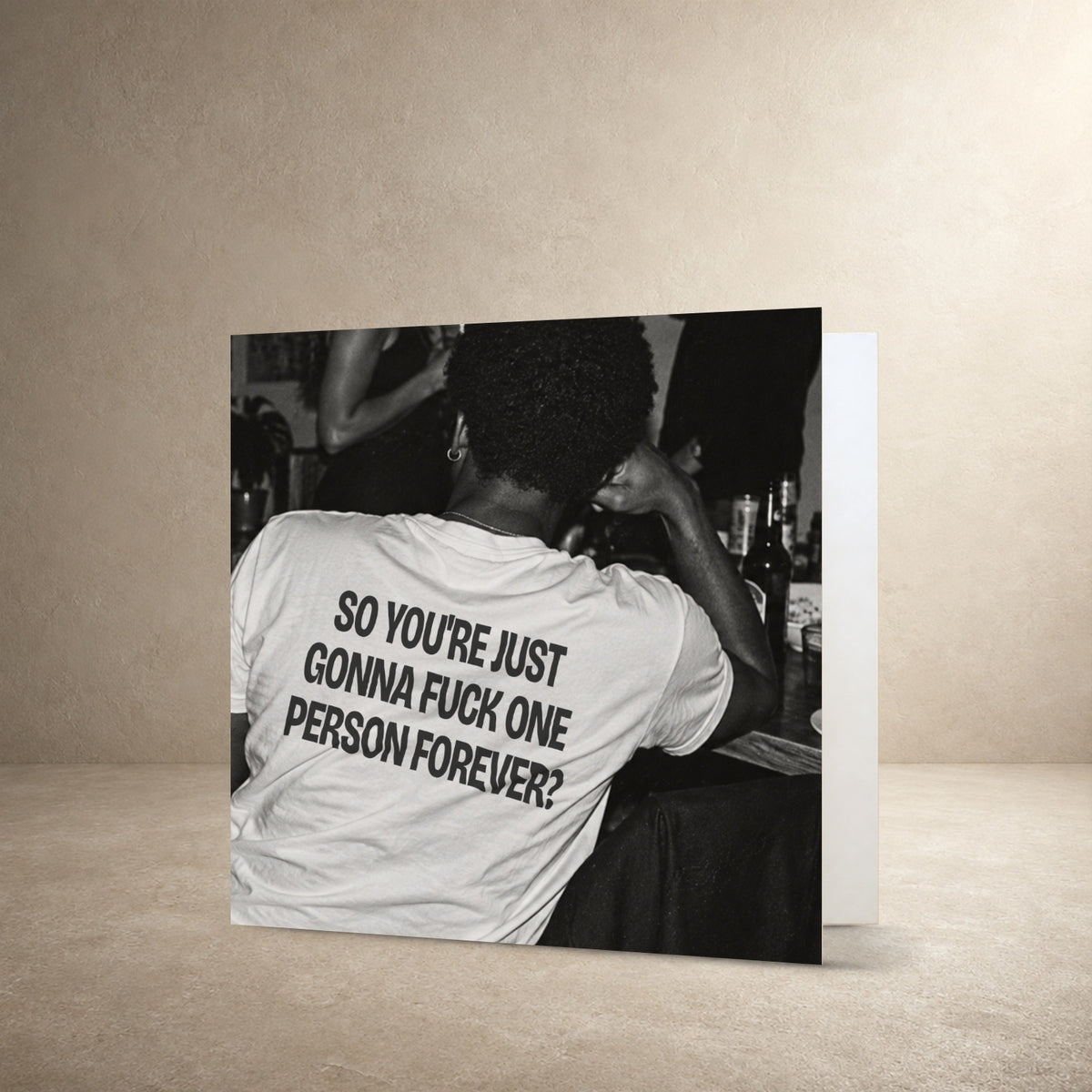 Black-and-white rear-view photograph of a person wearing a white T-shirt, with the message: “So you're just gonna fuck one person forever?”.