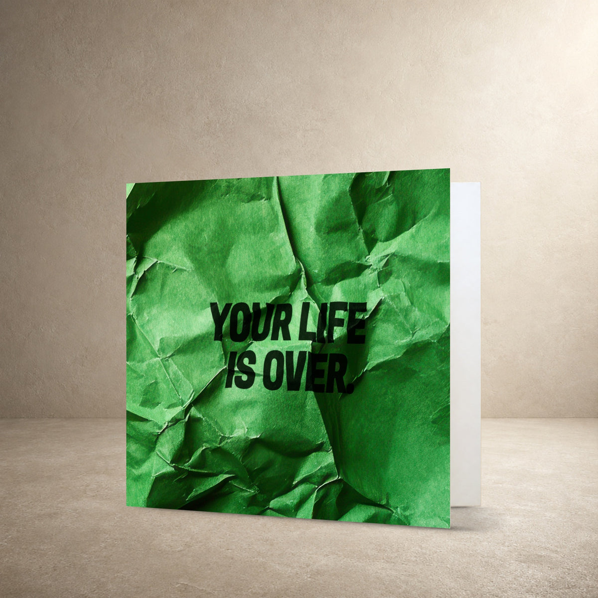 Bright green crumpled paper card front with realistic folds and texture, with the message: “Your life is over.”.