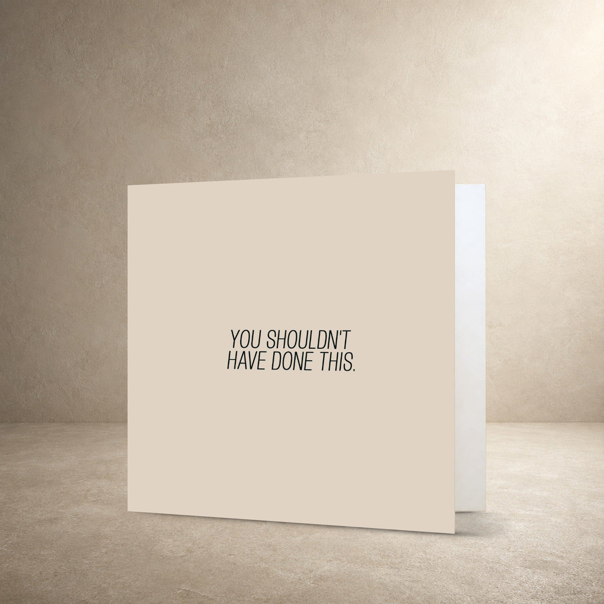 Minimal beige card front with a narrow centred typographic layout, with the message: “You shouldn't have done this.”.