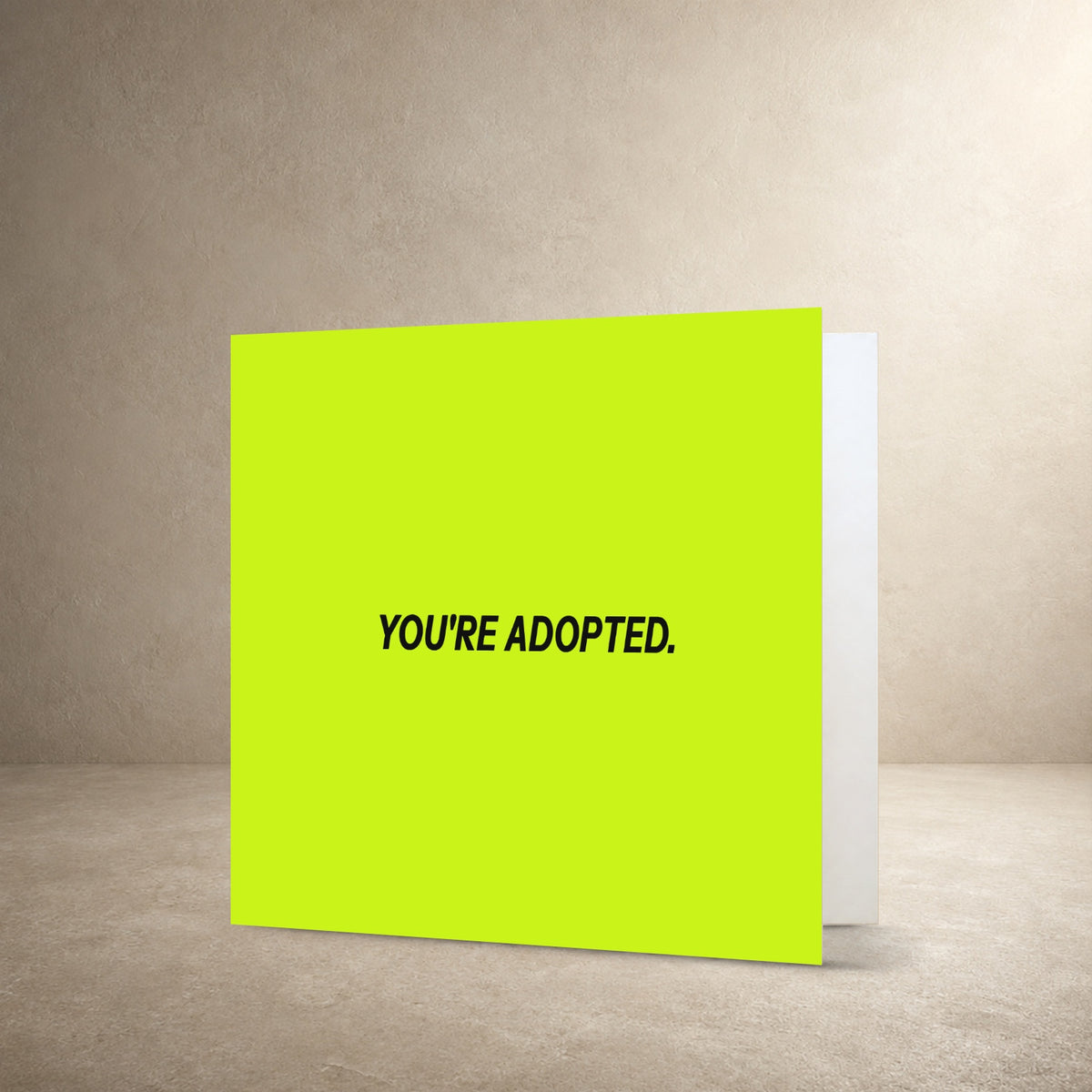 Minimal pale lime card front with bold dark centred typography, with the message: “You're adopted.”.
