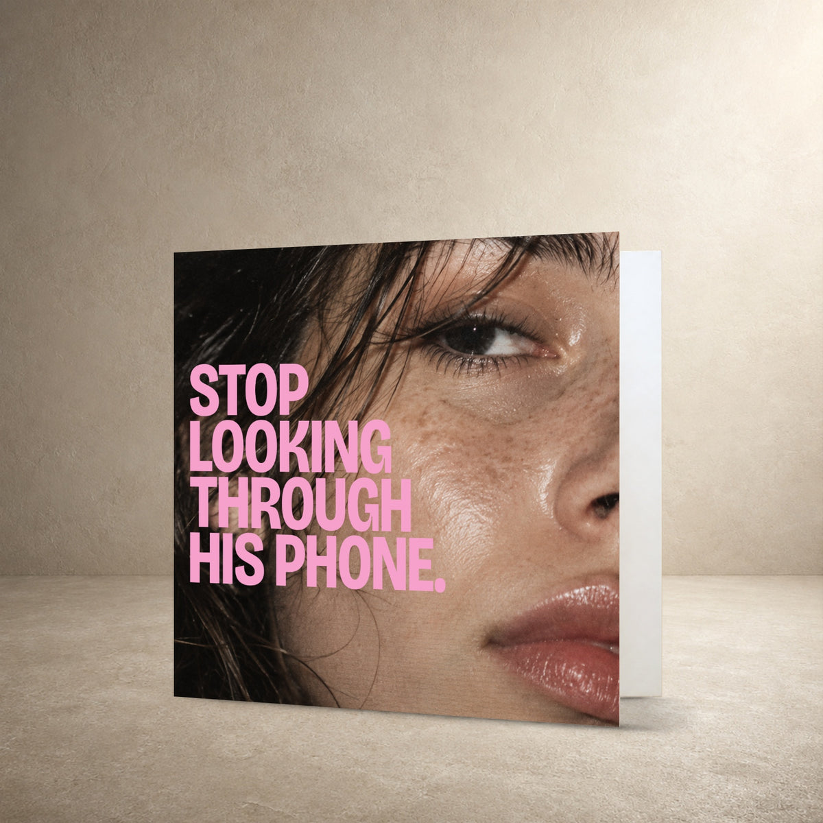 Close-up flash photograph of a face with dewy skin and dark hair, with the message: “Stop looking through his phone.”.