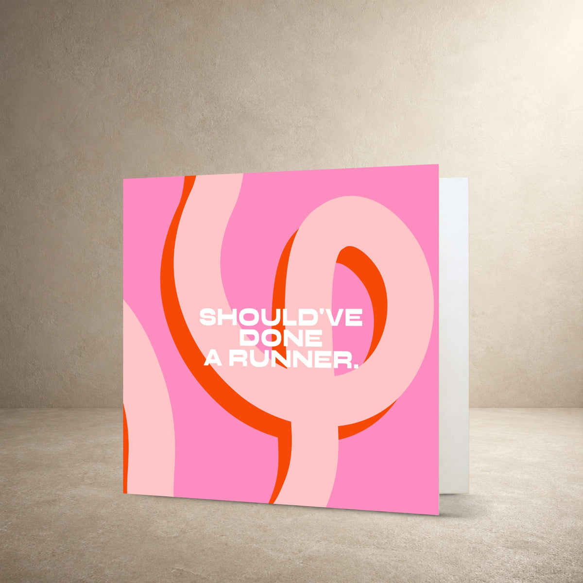 Bright pink card front with looping orange and pale pink abstract ribbon shapes, with the message: “Should've done a runner.”.