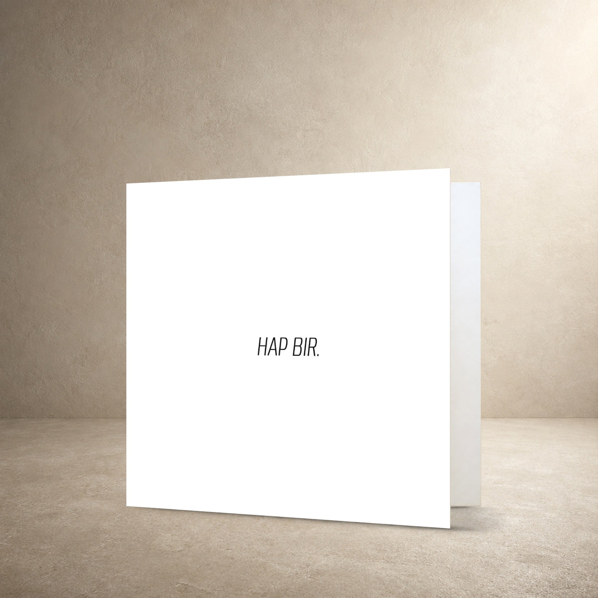 Minimal white card front with a small centred typographic layout, with the message: “Hap bir.”.