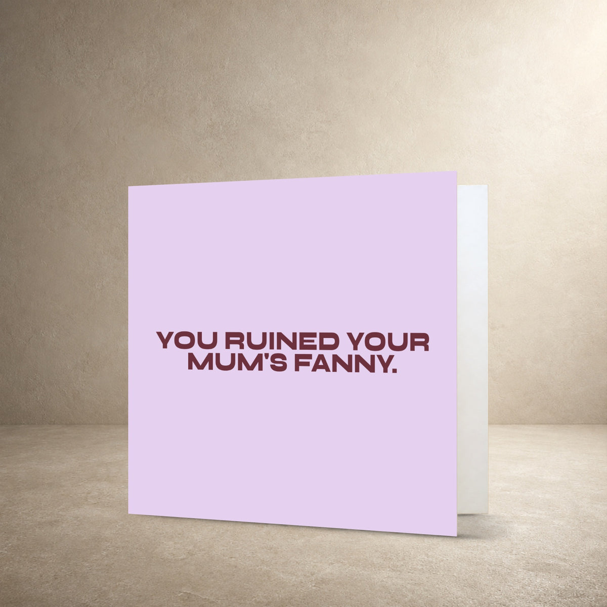 Pale lilac card front with burgundy typography, with the message: “You ruined your mum's fanny.”.